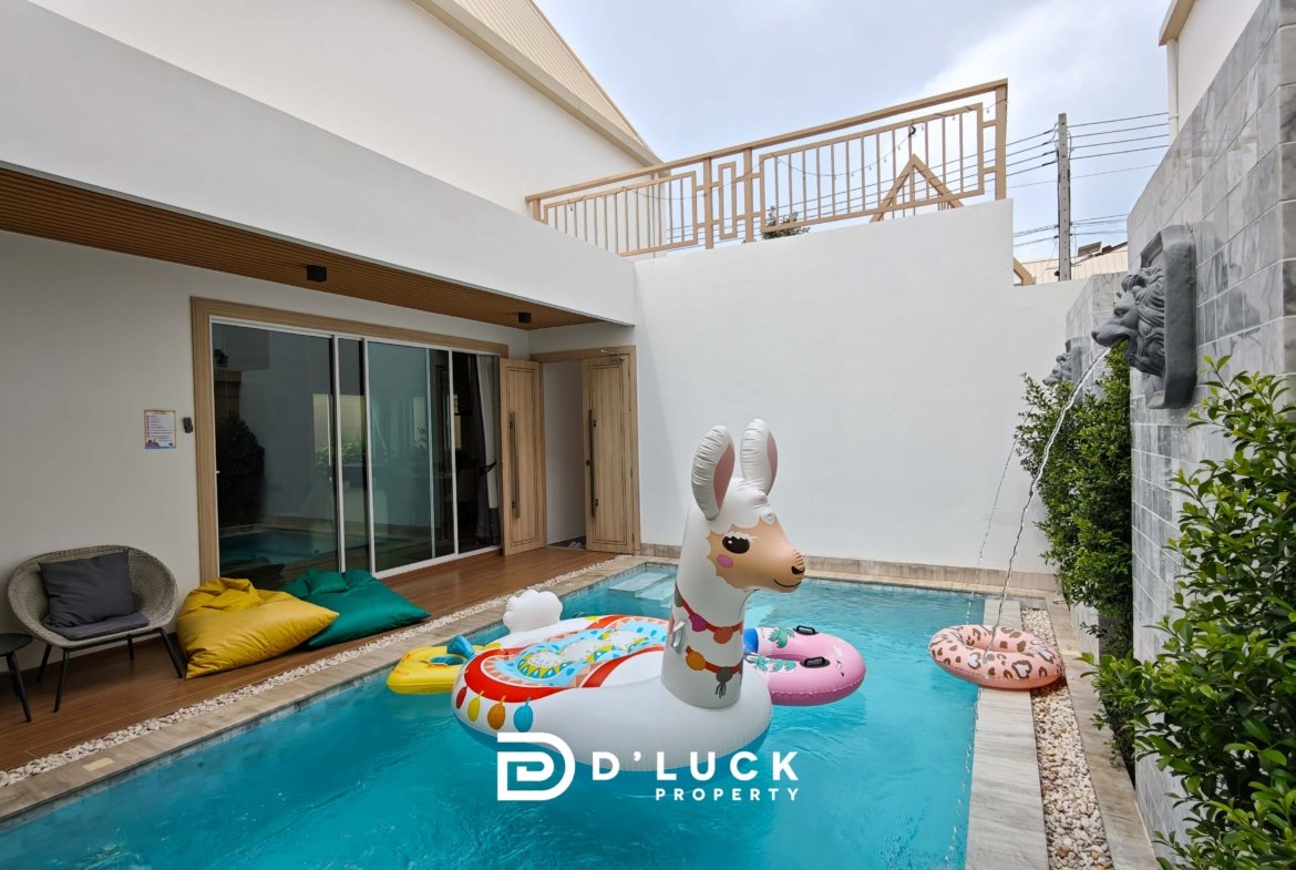 Pool area with inflatable animal floats (unicorn and flamingo) and colorful cushions by sliding glass doors.