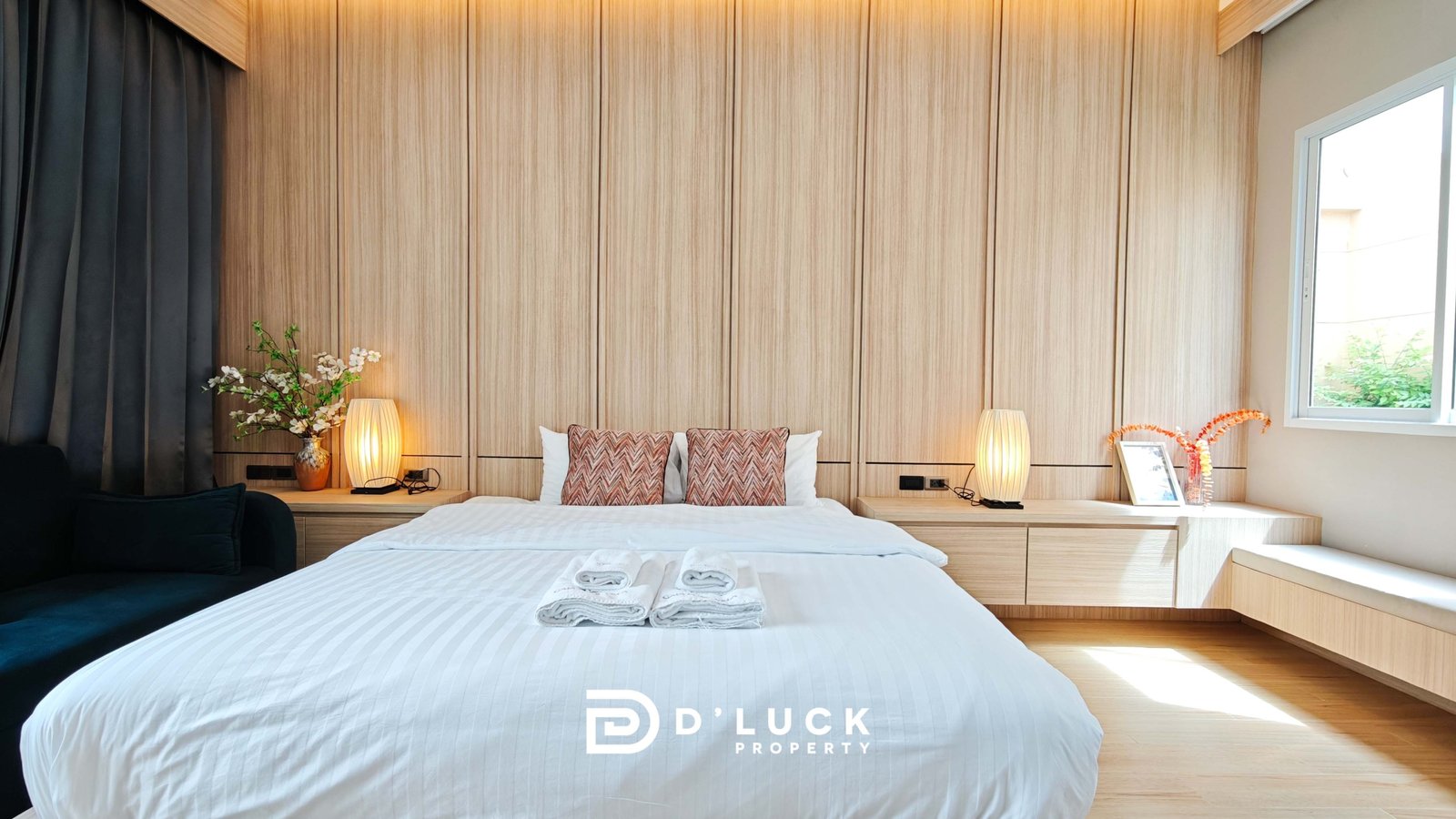 Modern hotel bedroom with a large wooden paneled headboard, white bedding, and matching lamps on both sides of the bed.