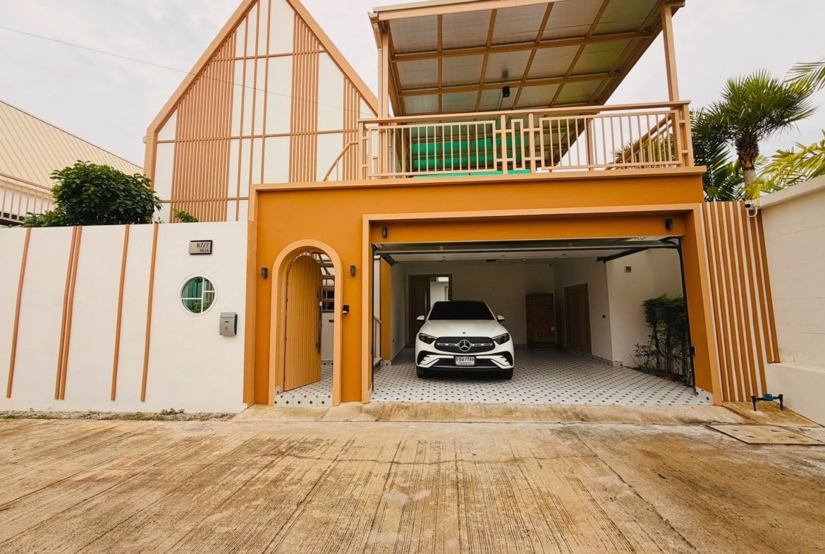 White Mercedes SUV parked in a covered carport of a modern orange-yellow house with striped walls and a circular window on the left.