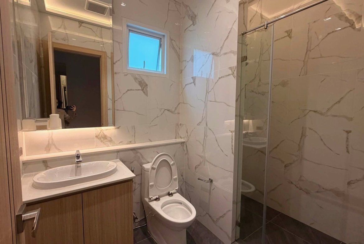 Marble-tiled bathroom with a wood vanity, oval sink, and glass shower enclosure