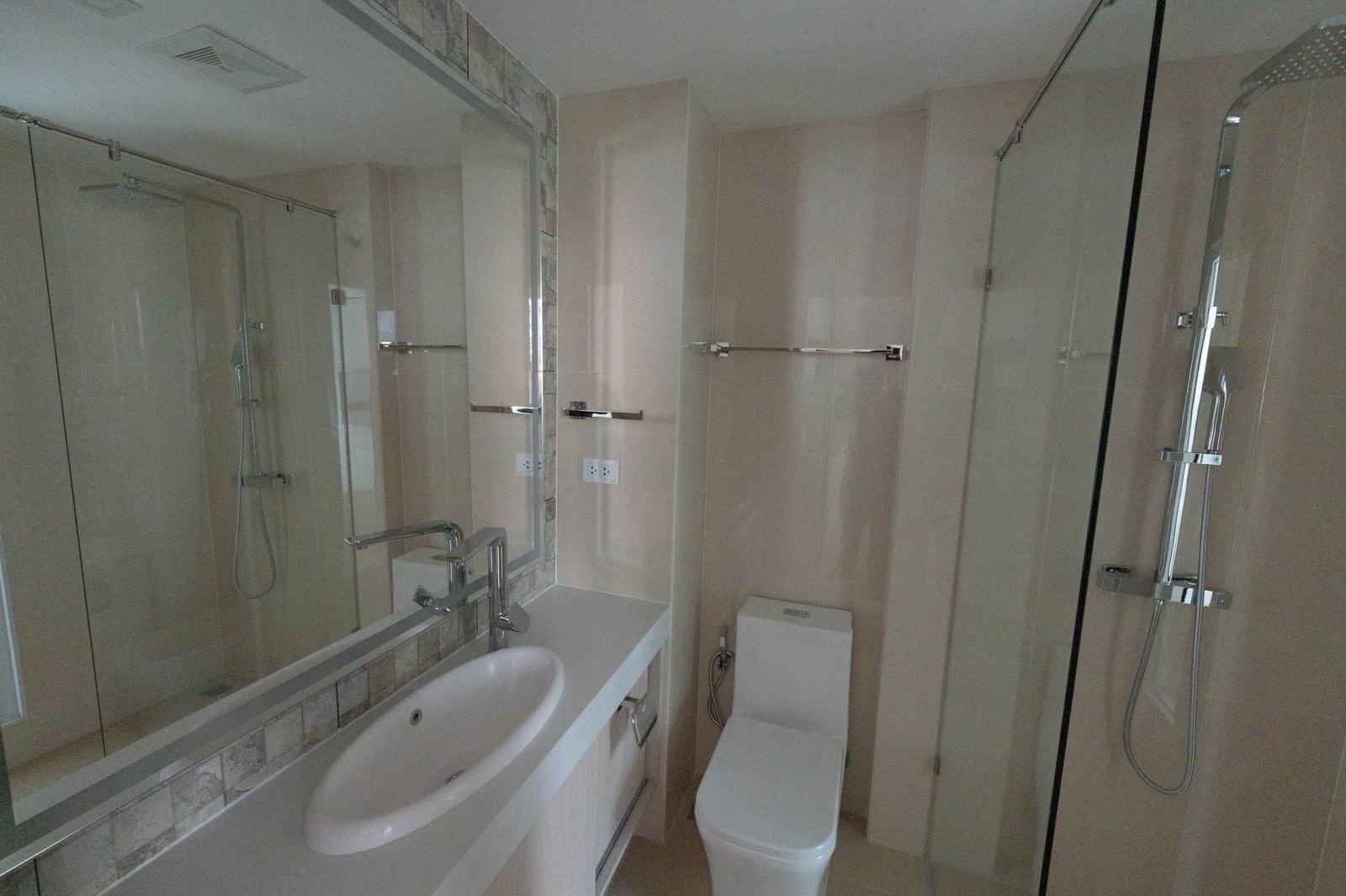 Olympus_C306_Rdl79A_6 Modern bathroom with glass shower enclosure, white sink, and wall-mounted towel bars.