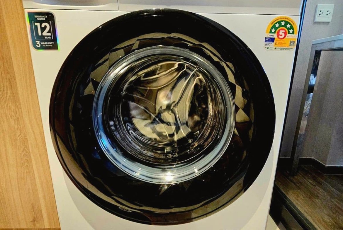 White Hisense front-loading washing machine with large circular door and control panel on top, in a showroom setting.