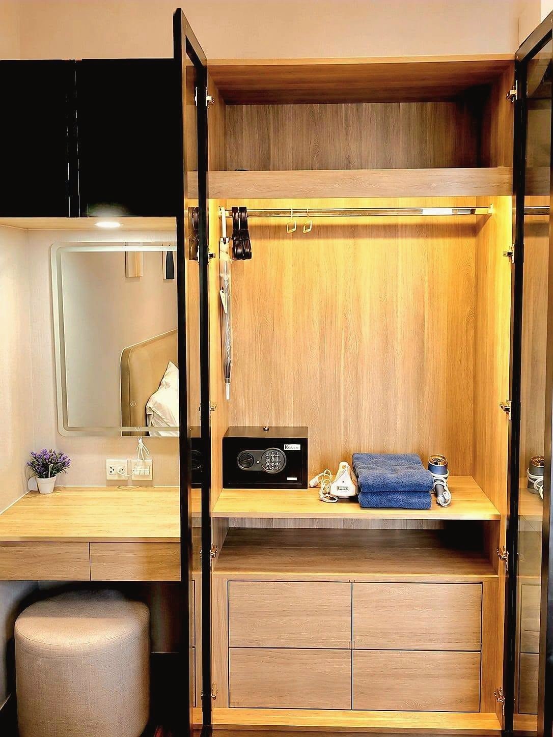 Once_Pattaya_Rent_Rdl337_8 Open wooden wardrobe with clothes rail and built-in safe; on the shelf: folded blue towels, a hair dryer, and a small safe keypad.