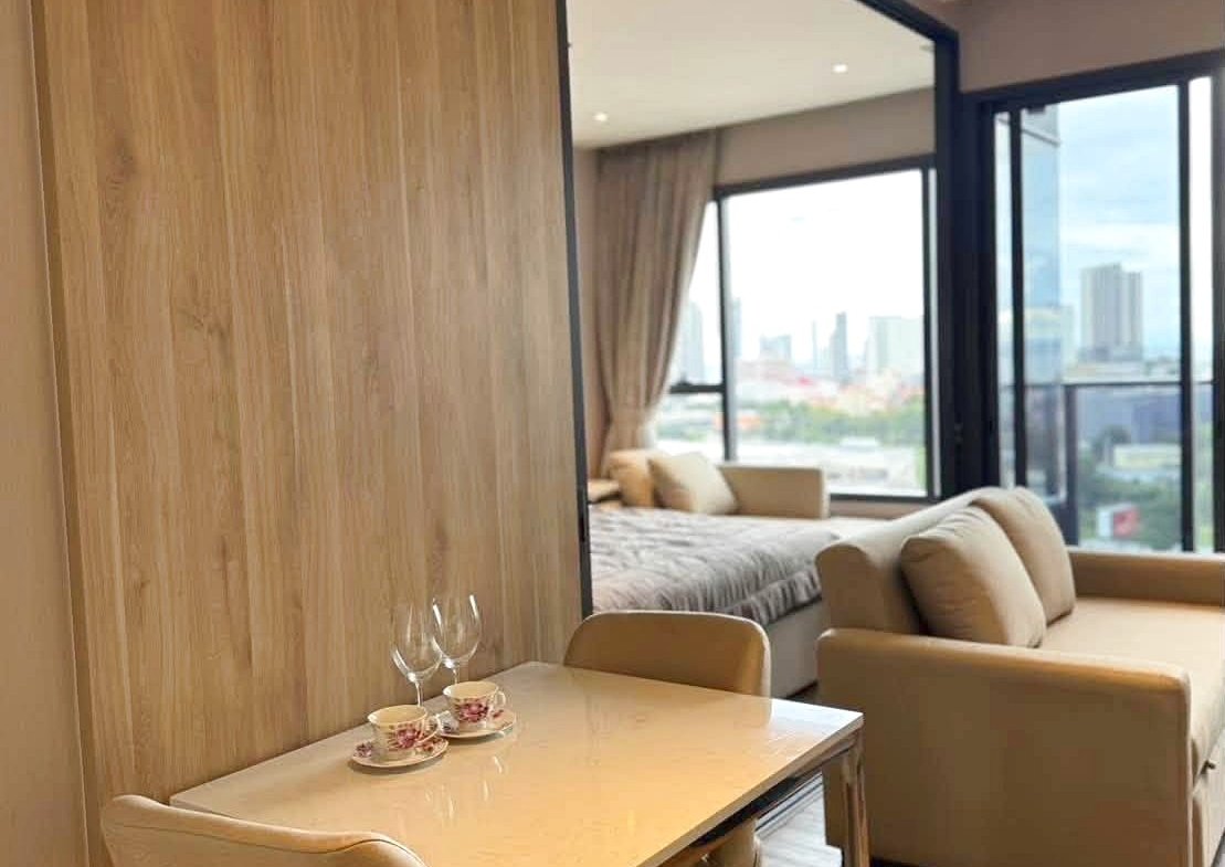 Dining table for two with teacups and glasses in a modern suite, wood-paneled wall and open living area with city views.