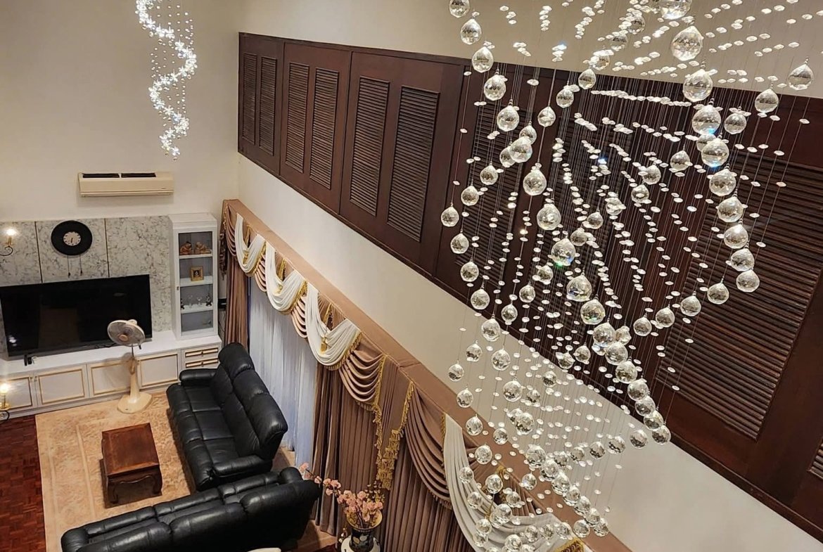 Luxurious living room with cascading crystal chandeliers, dark wood cabinets, and a marble fireplace surrounding a white dining table set.