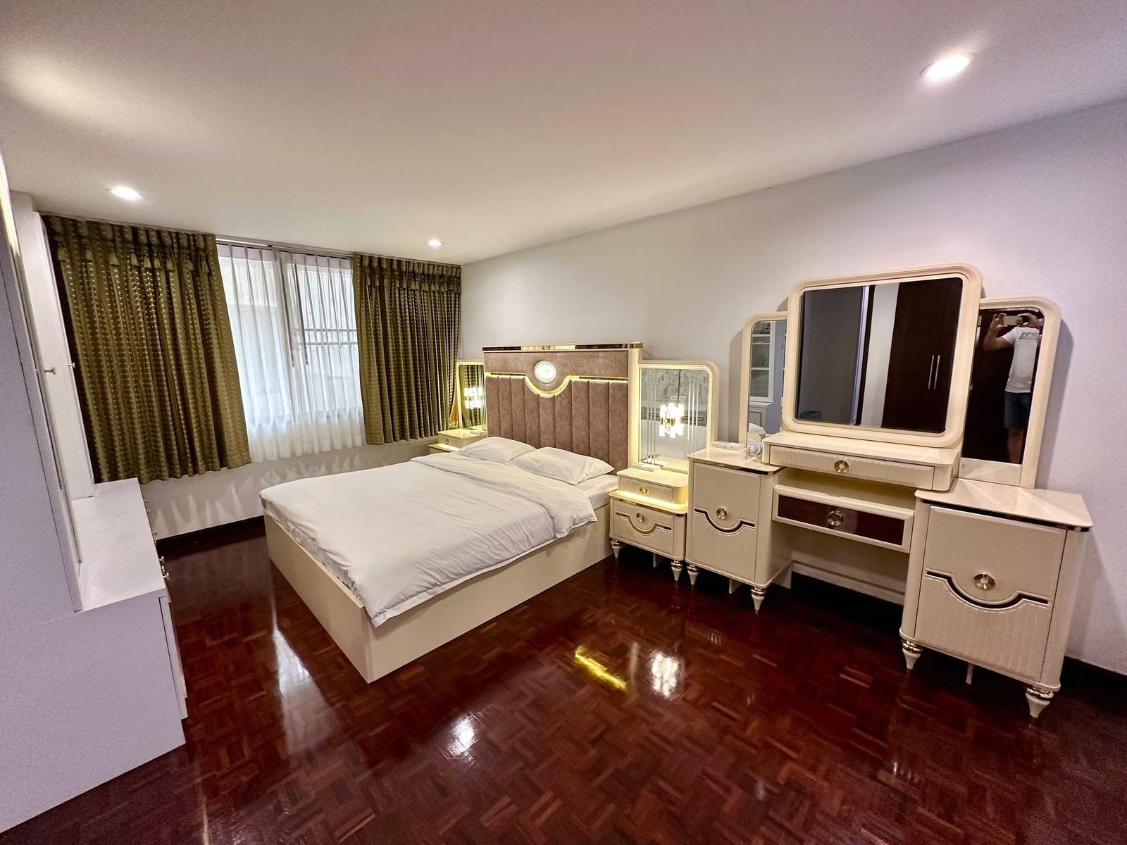PANCHALEA_RESIDENCE_Jomtien_Rdl290_5 Bright bedroom with white ornate furniture, a large bed, mirrored dresser, and dark wooden floor.