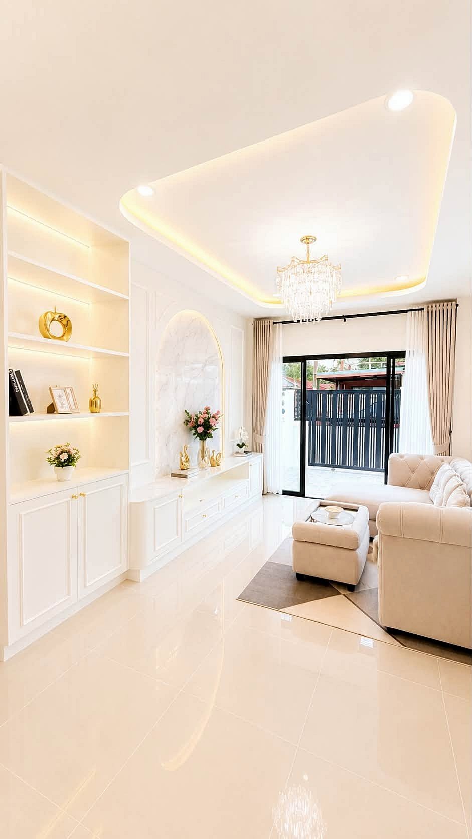 Pattaya_Rungruang_Sale_Dlh579_10 Elegant white living room with built-in shelves, gold decor accents, and a crystal chandelier.