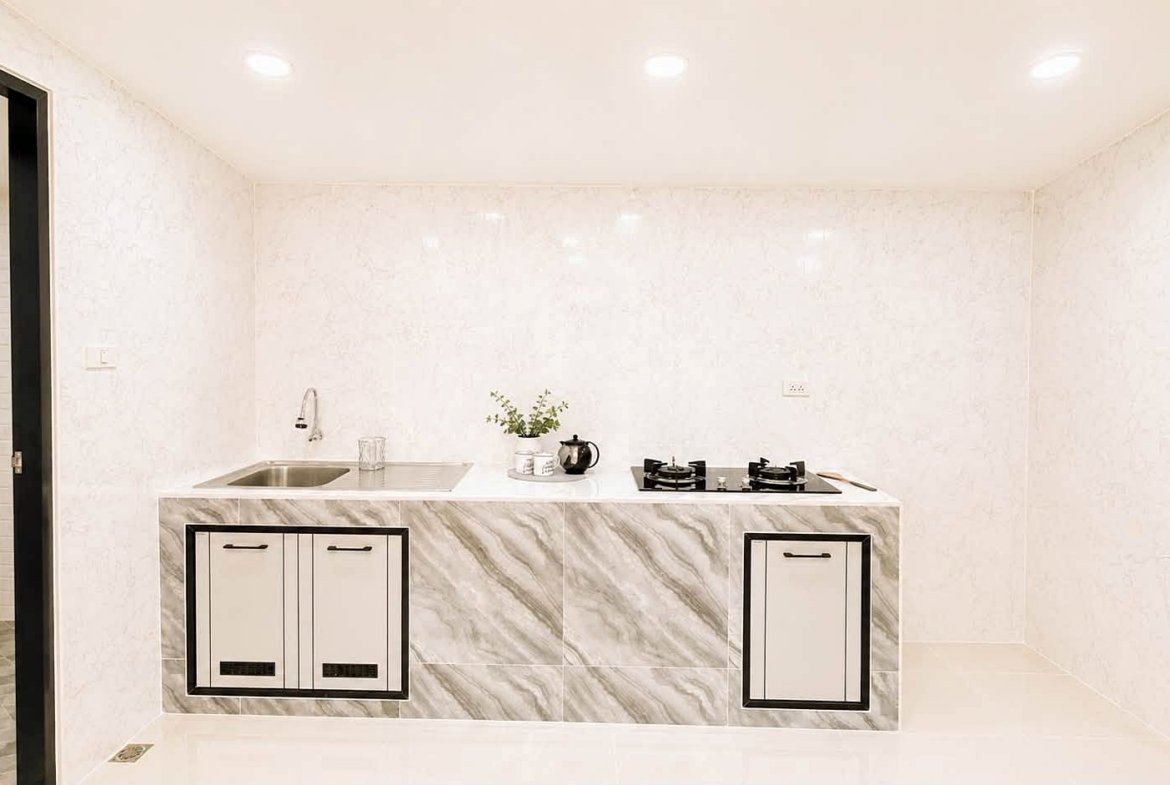 Modern white marble kitchen island with a double sink on the left, a two-burner gas stove on the right, and a kettle on the counter.