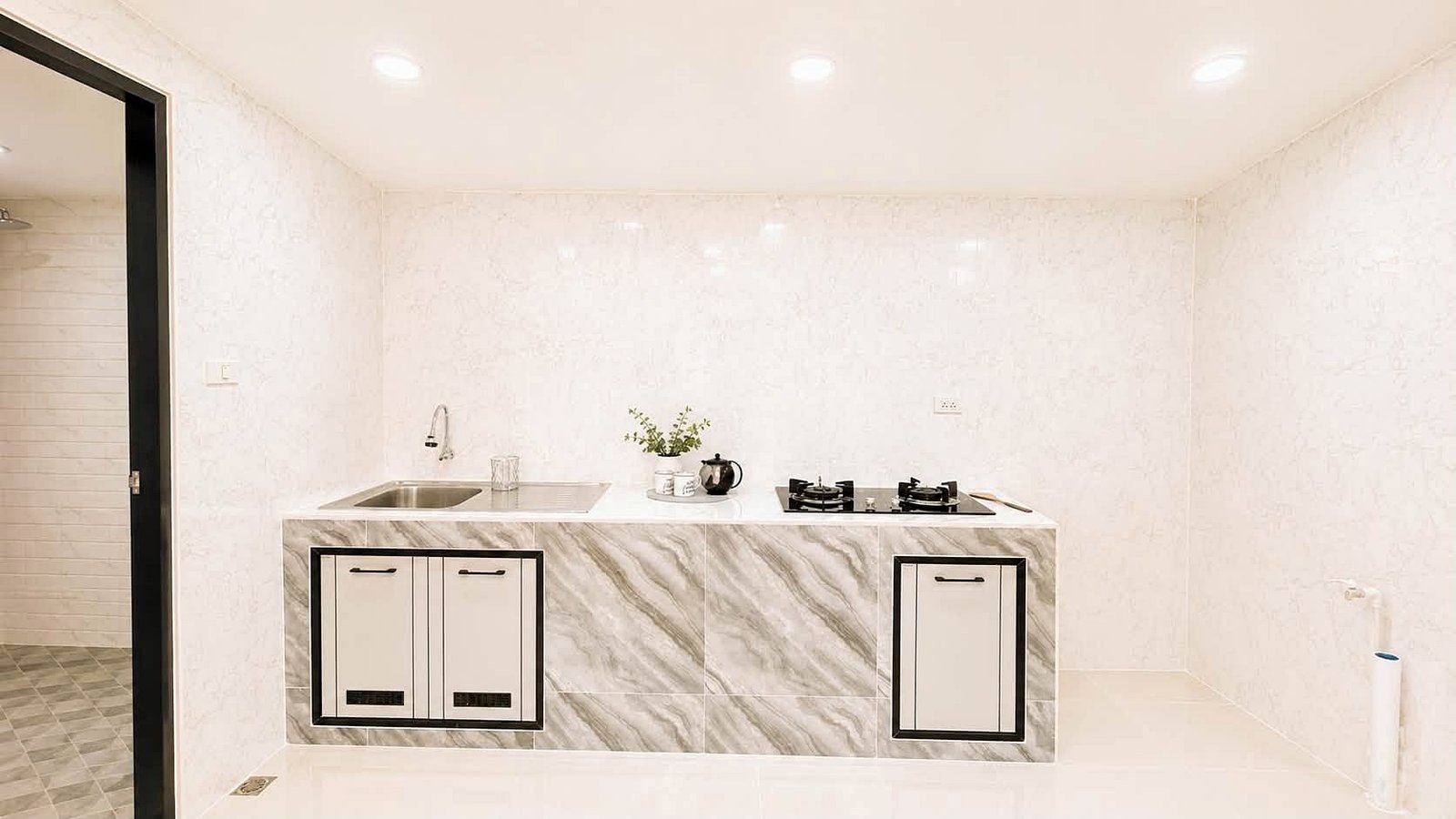 Pattaya_Rungruang_Sale_Dlh579_14 Modern white marble kitchen island with a double sink on the left, a two-burner gas stove on the right, and a kettle on the counter.
