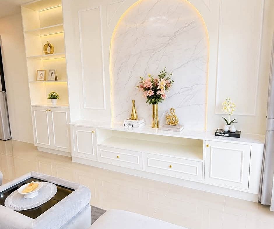 Luxurious white living room with a crystal chandelier and a marble arch niche displaying flowers and decor.