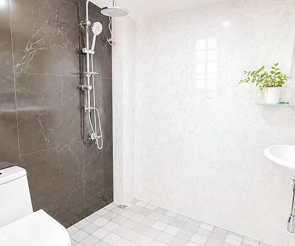Modern bathroom with a glassless shower panel on a dark marble wall, white toilet, and a small plant on a shelf.
