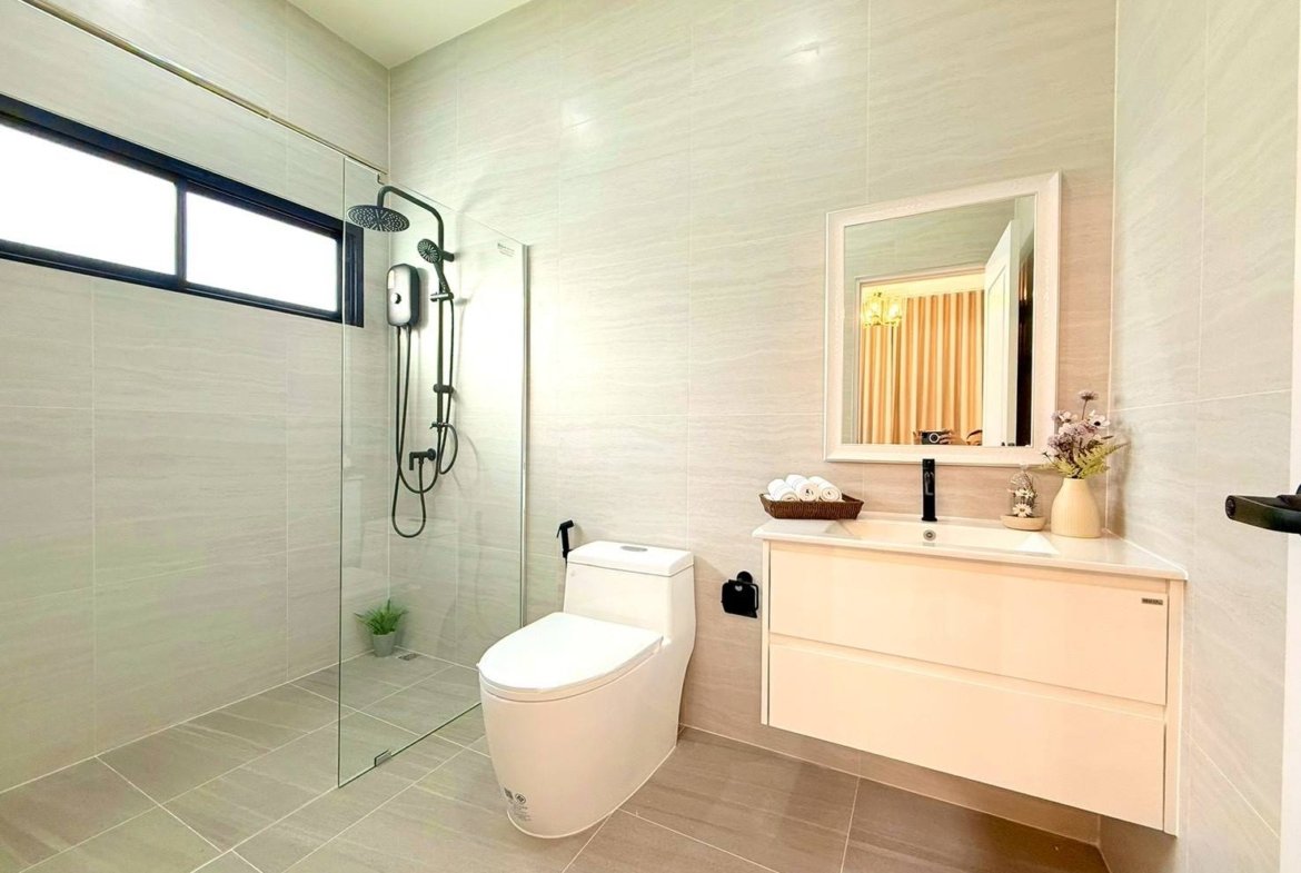 Modern bathroom with a glass-enclosed shower, wall-mounted vanity, and a white toilet.