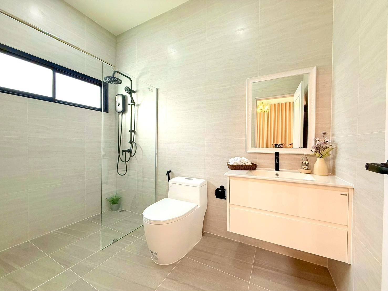 Pattaya_Tropical_2_Village_Dlh535_7 Modern bathroom with a glass-enclosed shower, wall-mounted vanity, and a white toilet.