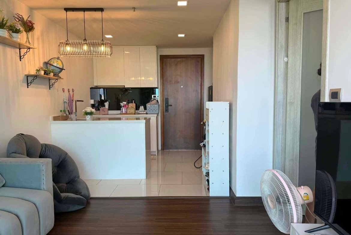 Open-plan living area with dark wood floor, white cabinetry, and a cage-style pendant light hanging over a kitchen island.