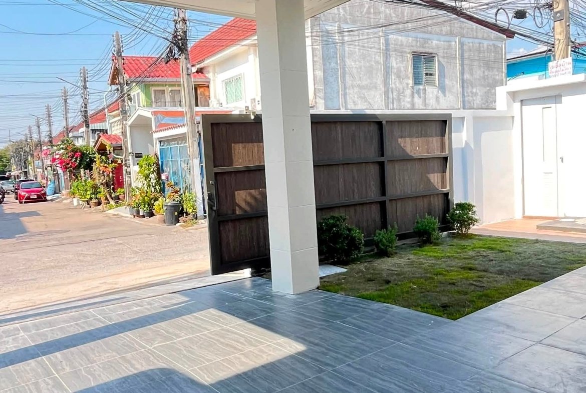 Covered patio with a gray tiled floor and white column, overlooking a residential street with utility poles and tangled wires.