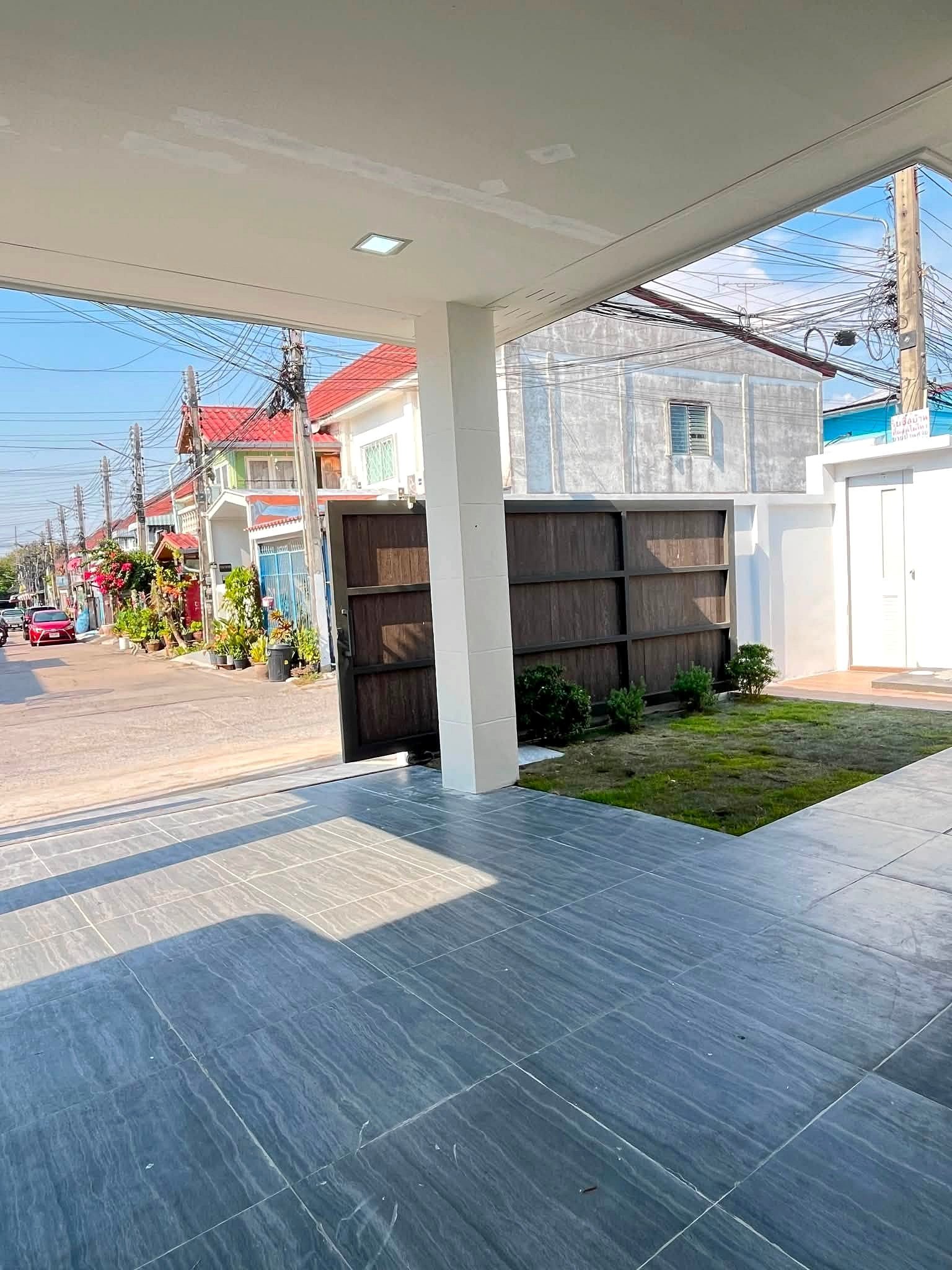 Covered patio with a gray tiled floor and white column, overlooking a residential street with utility poles and tangled wires.