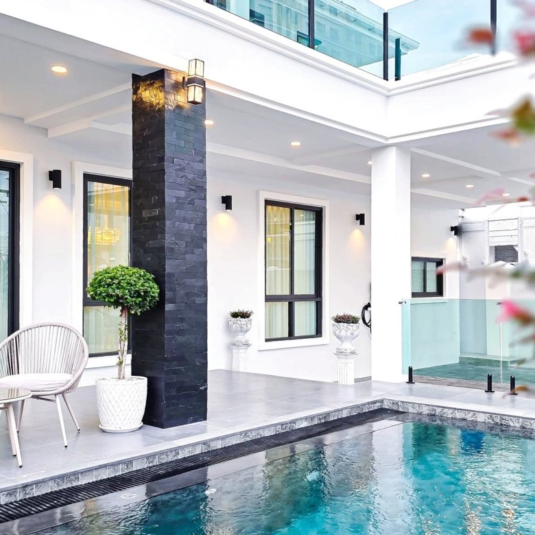 Modern poolside patio with white walls black stone pillar glass doors and outdoor seating by the pool