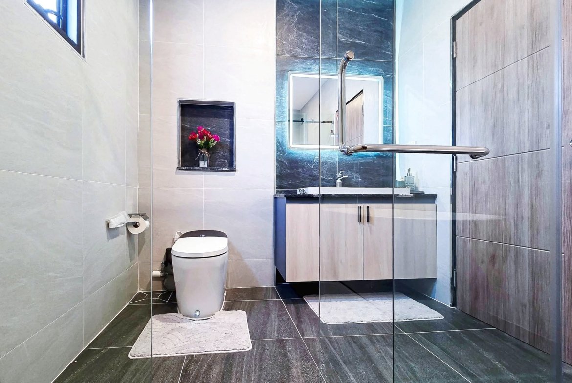 Contemporary bathroom with a glass shower enclosure, toilet, and a vanity; pink flowers in a recessed shelf.