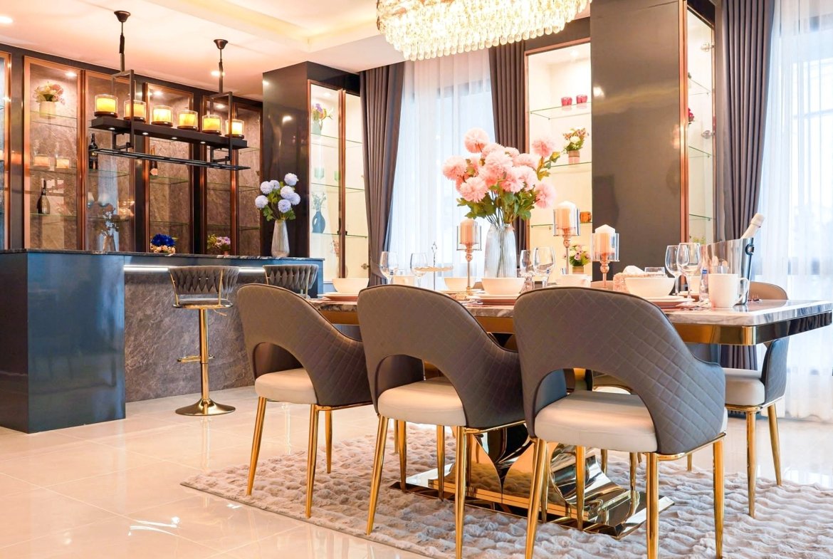 Luxurious dining room with a marble table set for a formal meal, pink flowers centerpiece, chandelier, and glass display cabinets.