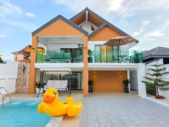 Modern two story house with orange siding glass balcony and a swimming pool with a large yellow inflatable duck in the foreground