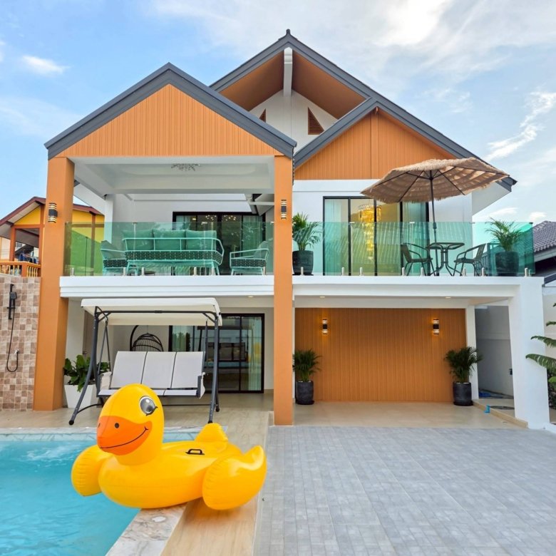 Modern two story house with orange siding glass balcony and a swimming pool with a large yellow inflatable duck in the foreground