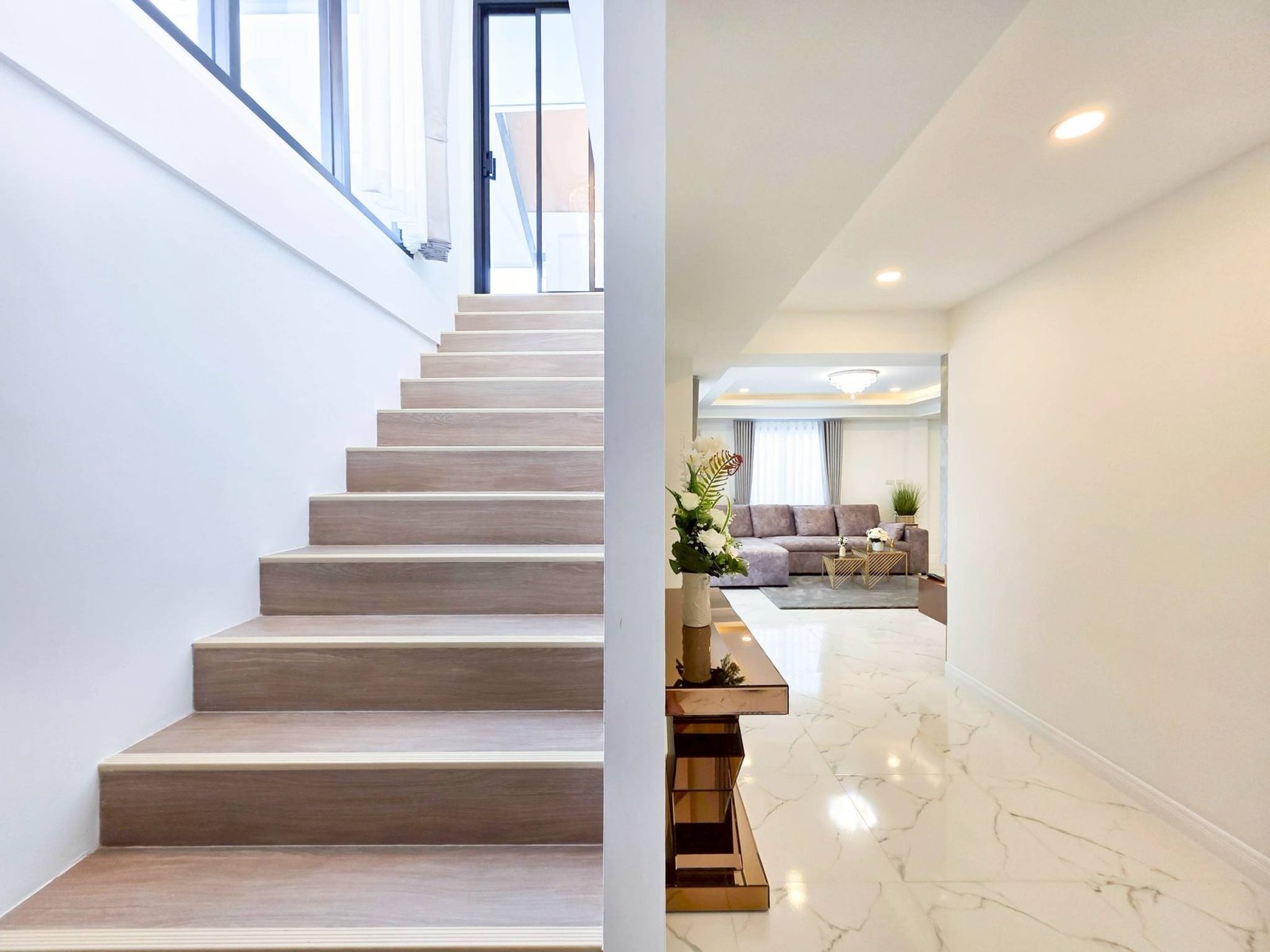 Pool_Villa_South_Pattaya_Sale_Dlh498_22 Modern interior split view: wooden staircase on the left and a living area with marble flooring on the right.