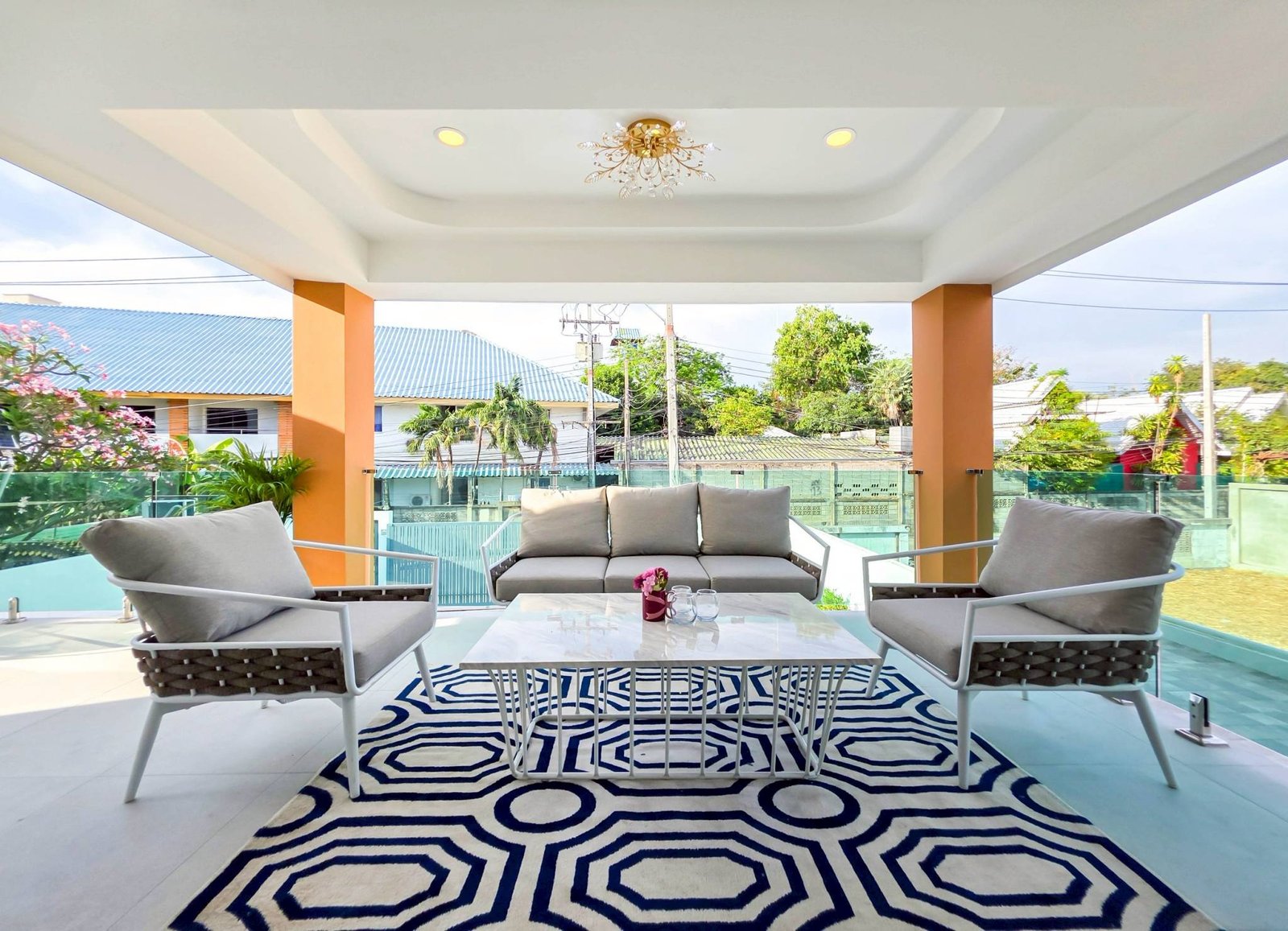 Pool_Villa_South_Pattaya_Sale_Dlh498_29 Covered outdoor seating area with cream sofas, white coffee table, and a bold black-and-white geometric rug under a decorative chandelier.
