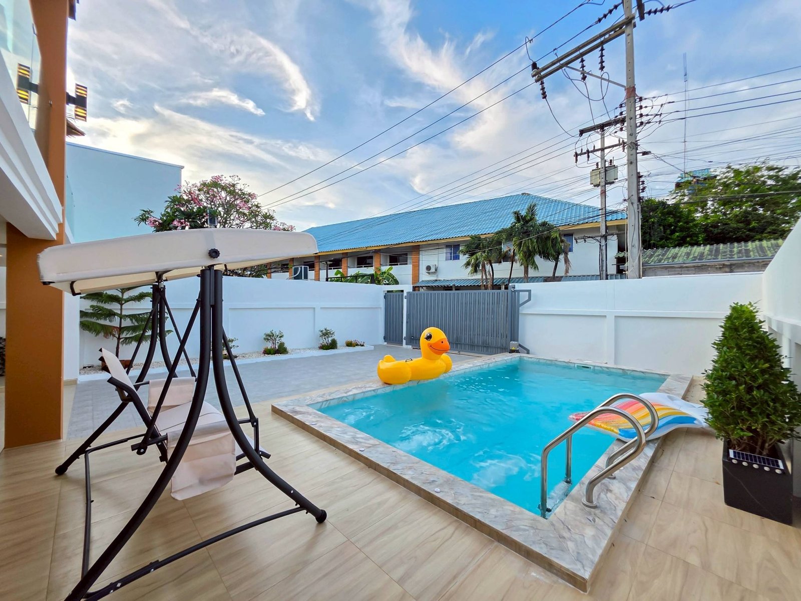 Pool_Villa_South_Pattaya_Sale_Dlh498_35 Poolside backyard with a yellow inflatable duck, lounge chairs, and a swing frame over light wood decking.