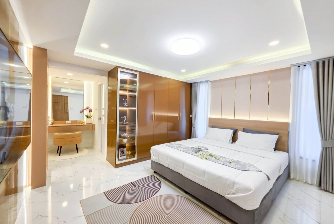 Modern hotel-style bedroom with two neatly made beds, brown wooden wardrobes, and marble flooring.