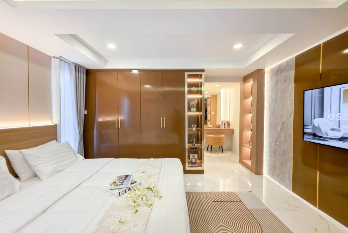 Modern hotel bedroom with two white beds, brown built-in wardrobes, and a glass display cabinet in a sleek suite.