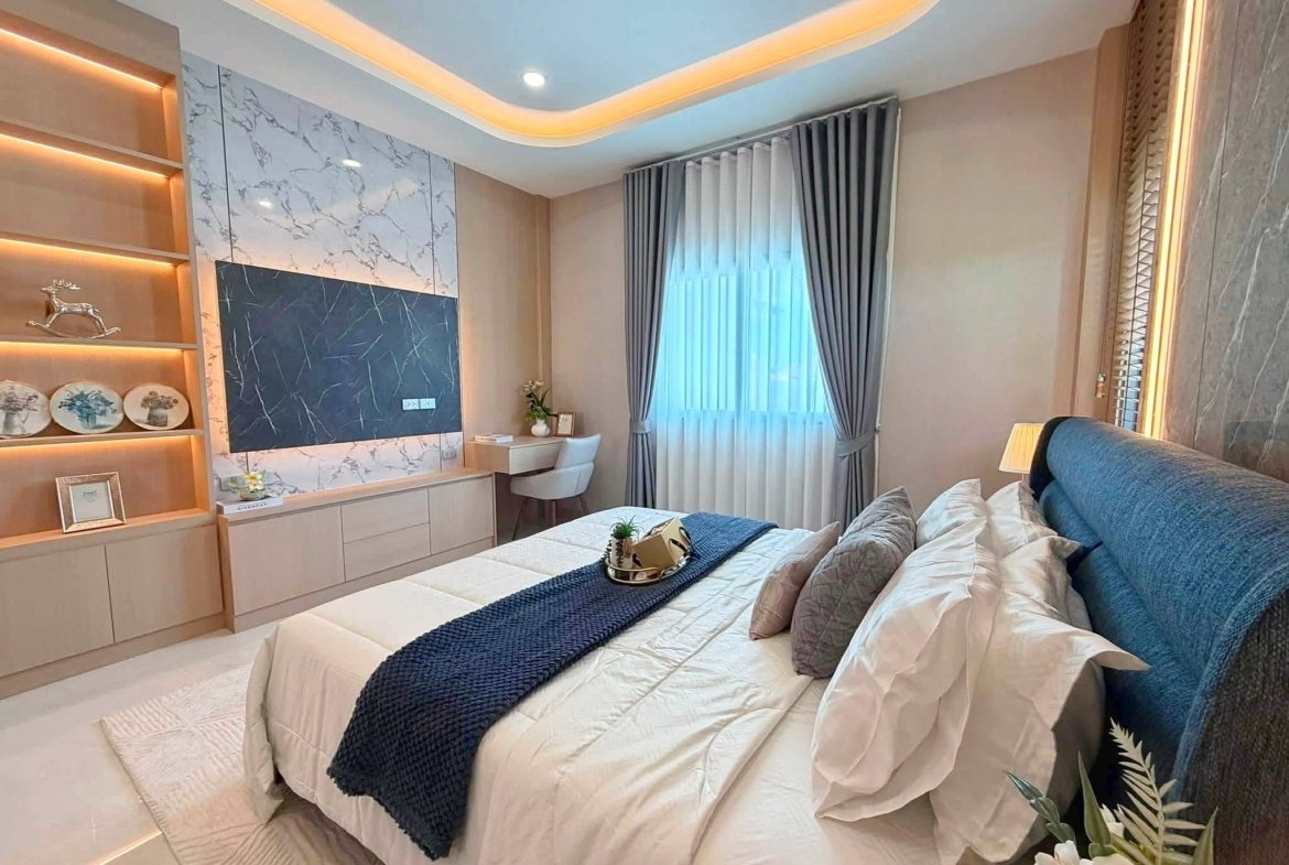 Contemporary bedroom with two neatly made beds, white linens, and navy bed runners under warm ambient lighting.