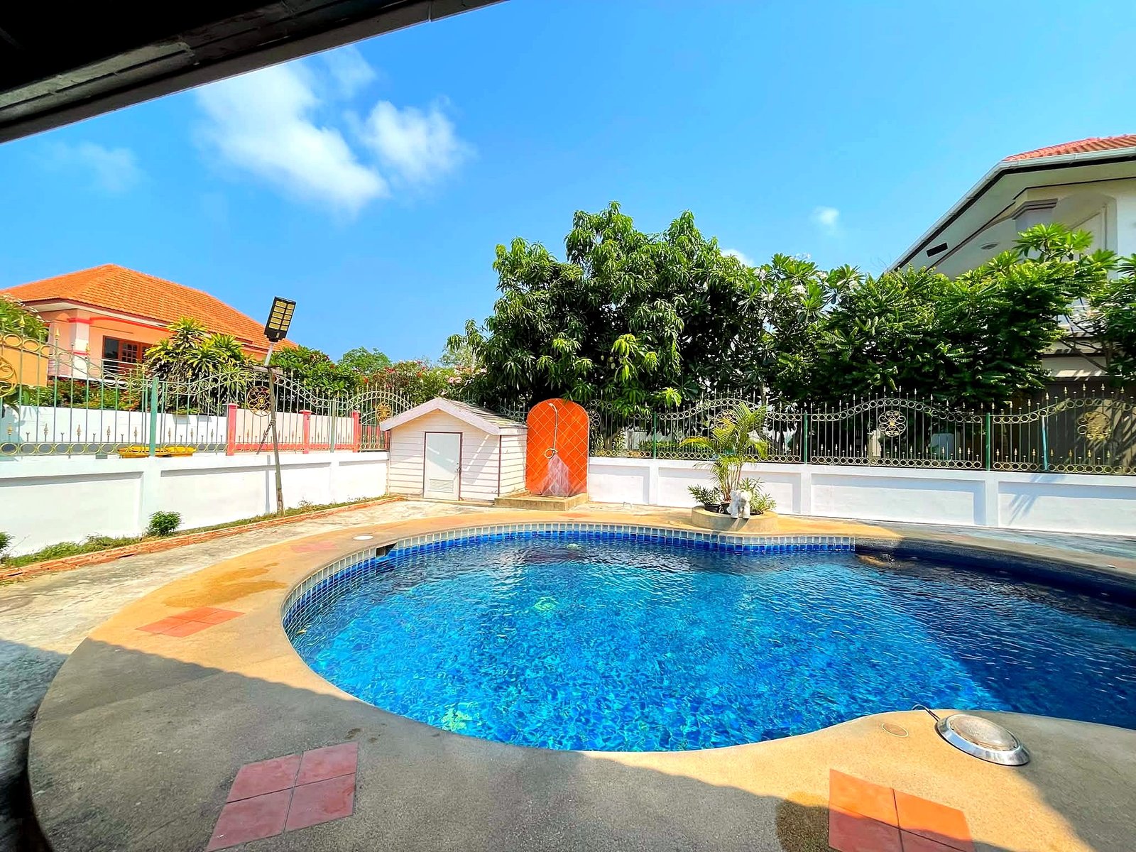 Poolvilla_Pattaya_Rent_Rdl352_2 Outdoor swimming pool with blue water, turquoise tiles, and surrounding concrete deck amid a white fence and tropical trees under a clear blue sky