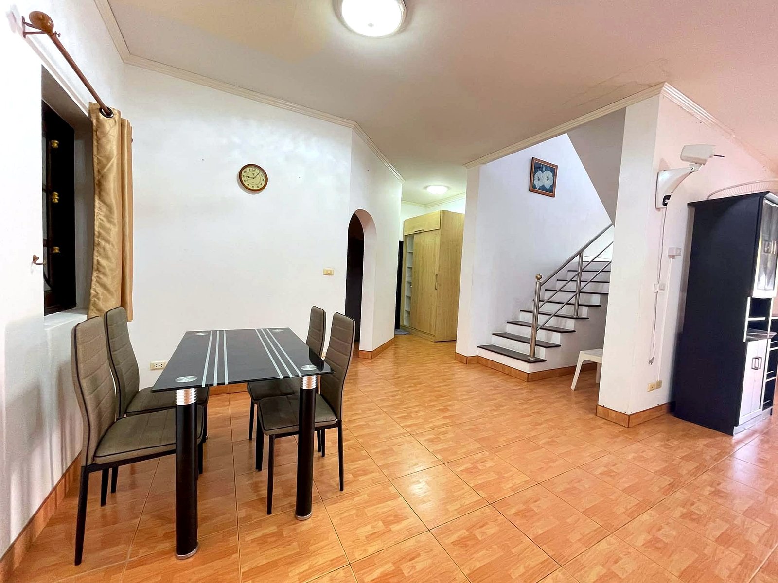 Poolvilla_Pattaya_Rent_Rdl352_4 Dining area with a glass tabletop and gray upholstered chairs, tiled floor, and a staircase on the right.