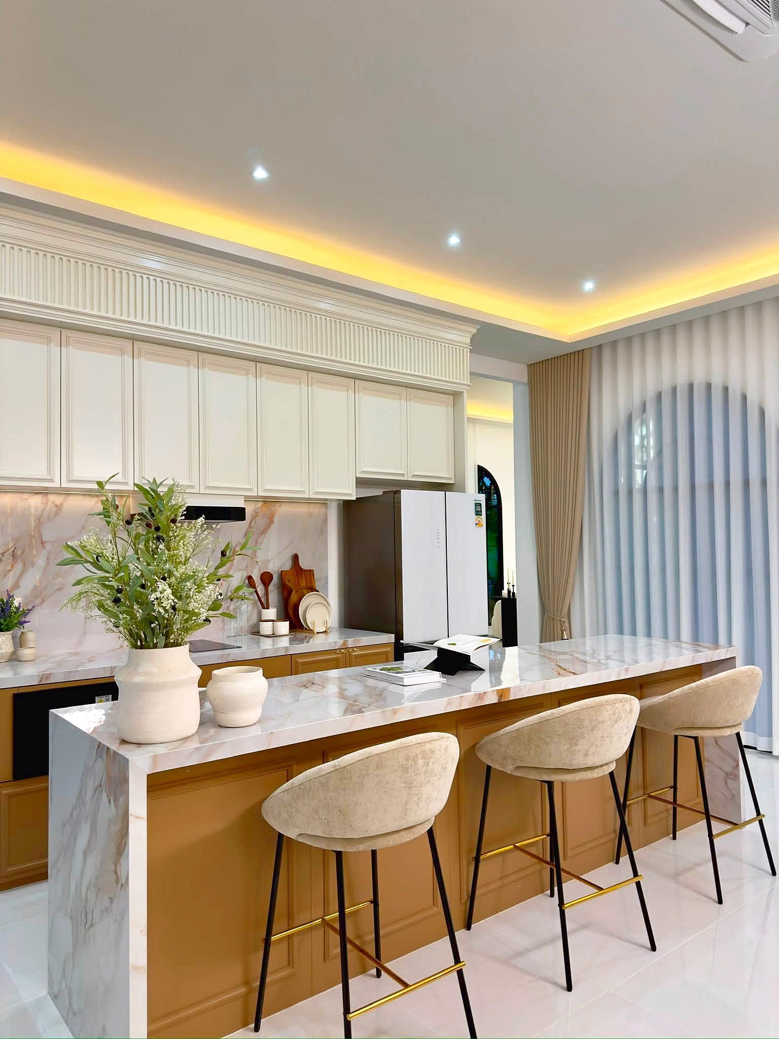 Poolvilla_Soi_Siam_Pattaya_Dlh584_19 Modern kitchen with marble island, white cabinets, and beige upholstered bar stools along a marble countertop.