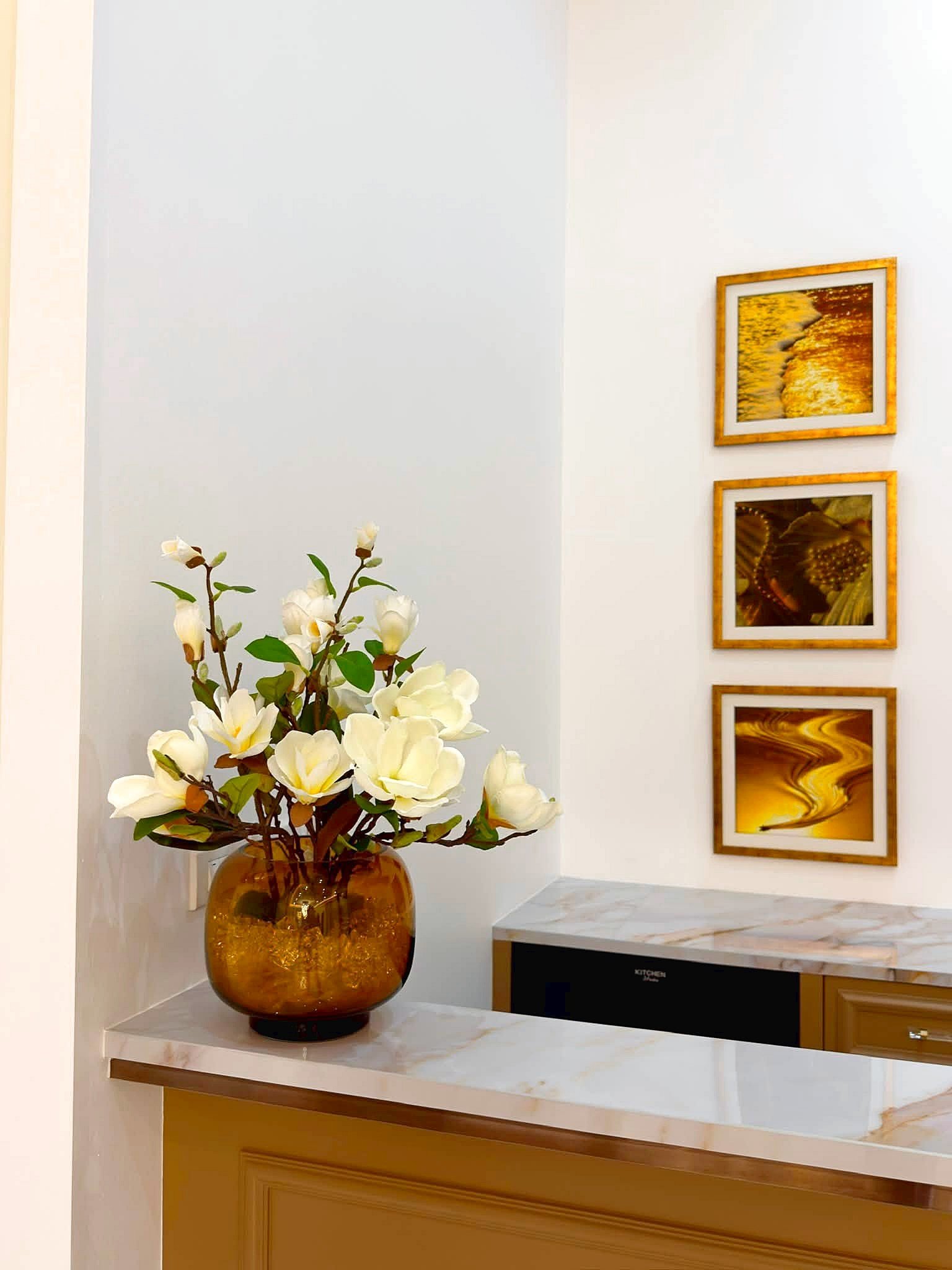 Poolvilla_Soi_Siam_Pattaya_Dlh584_8 Amber glass vase with white magnolia flowers on a marble counter, with gold-framed wall art to the right.