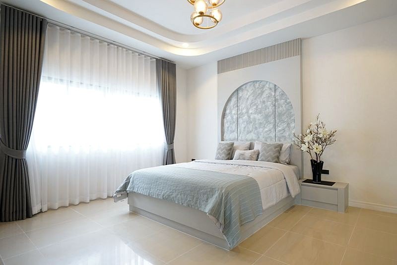 Bright modern bedroom with a low platform bed, pale blue bedding, and a rounded headboard panel above the pillows.