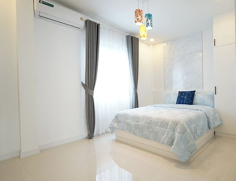 Bright modern bedroom with white walls, marble accent wall behind the bed, and blue bedding.