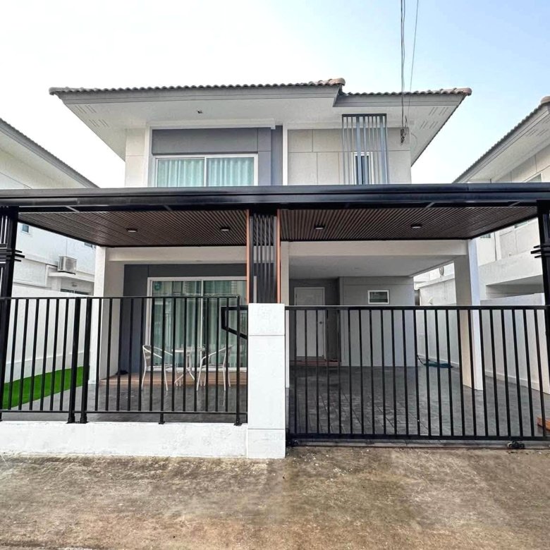 Front view of a modern row of white townhouses with a covered carport black metal fence and gated entrance