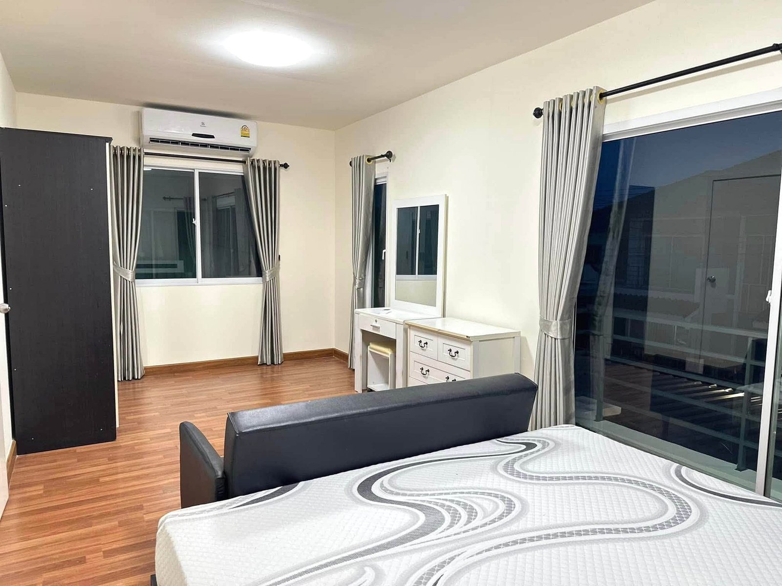 Pruksa_Nara_Pattaya_Rent_Rdl351_12 Hotel-style bedroom with two matching beds, dresser, mirror, and large windows with gray curtains.
