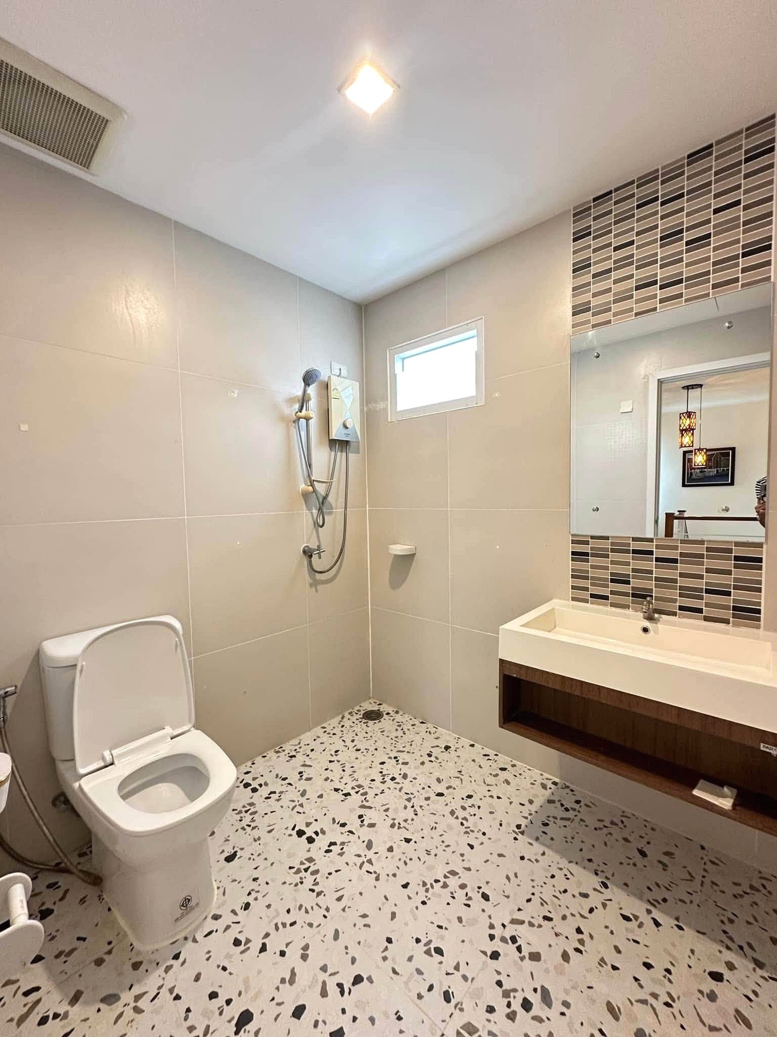 Pruksa_Nara_Pattaya_Rent_Rdl351_9 Modern bathroom with terrazzo floor, wall tiles, a walk-in shower, and a rectangular mirror above a white sink.