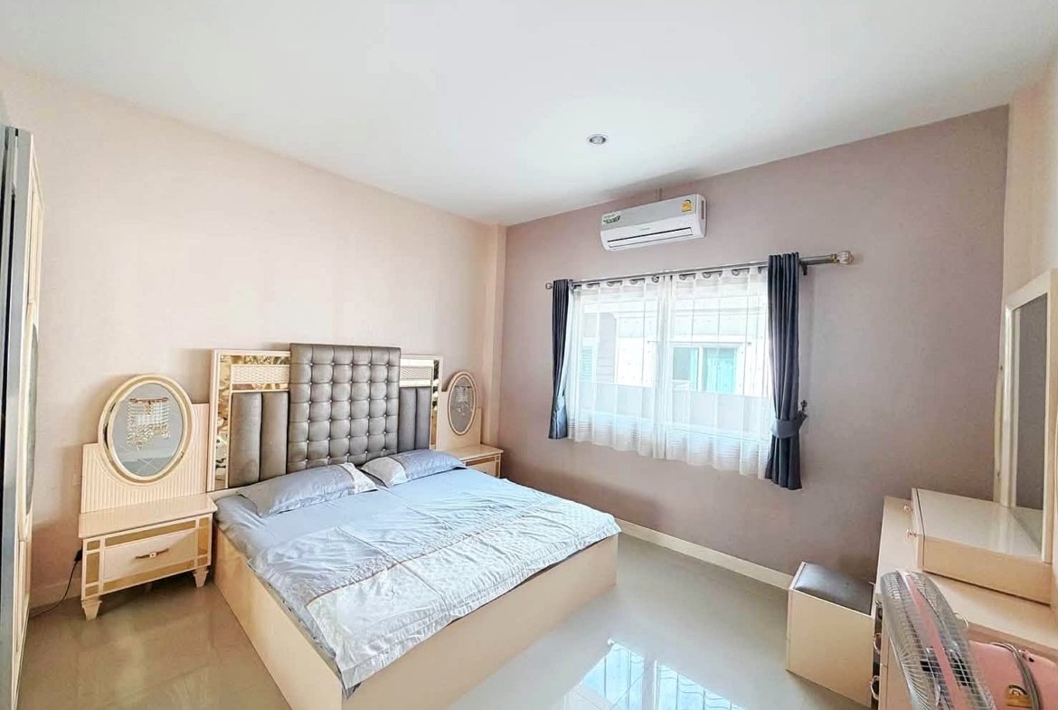 Bright bedroom with a large upholstered headboard bed and matching nightstands with round mirrors on either side of the bed