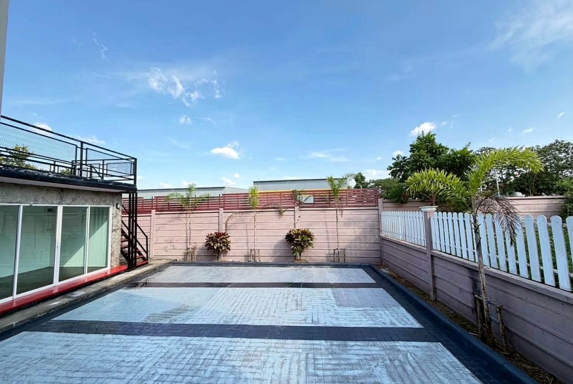 Outdoor backyard with a stamped concrete pool area, pale blue tiles, and surrounding fences under a clear sky