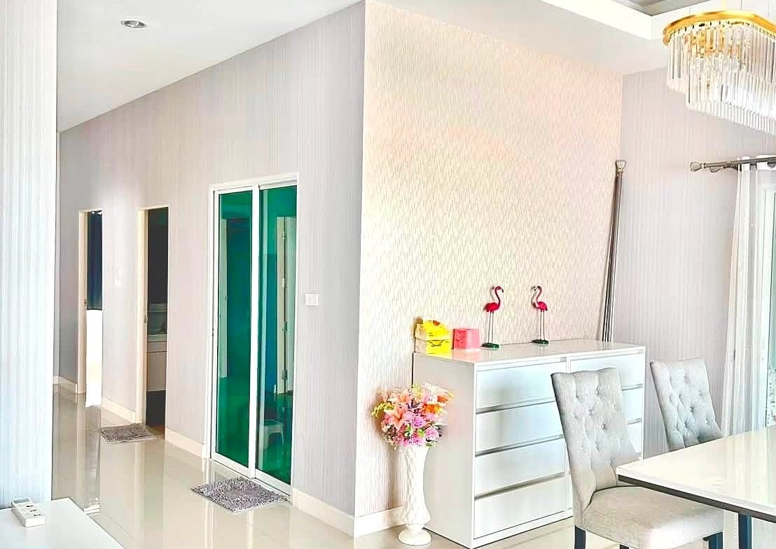 Bright, modern dining area with white furniture, glass green-tinted doors, and a chandelier