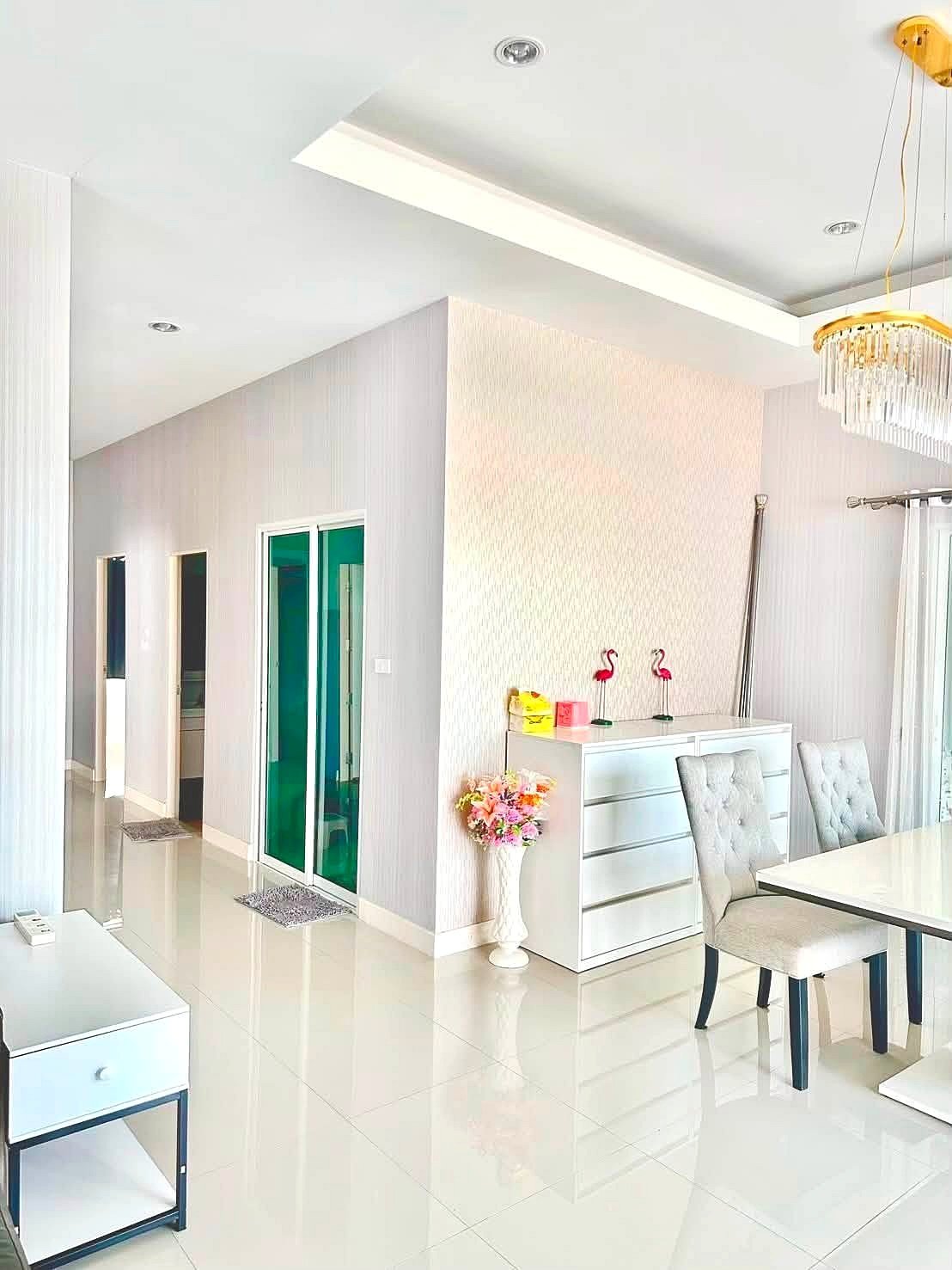 Raviporn_Romsai_Village_Dlh580_9 Bright, modern dining area with white furniture, glass green-tinted doors, and a chandelier