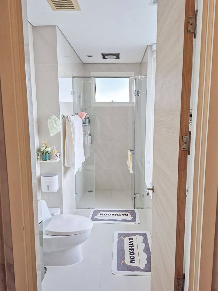 Reflection_Jomtien_Sale_Rent_Dlc242_10 Bright modern bathroom: glass-walled shower, white tiles, towels on a rack, and two 'BATHROOM' mats on the floor.