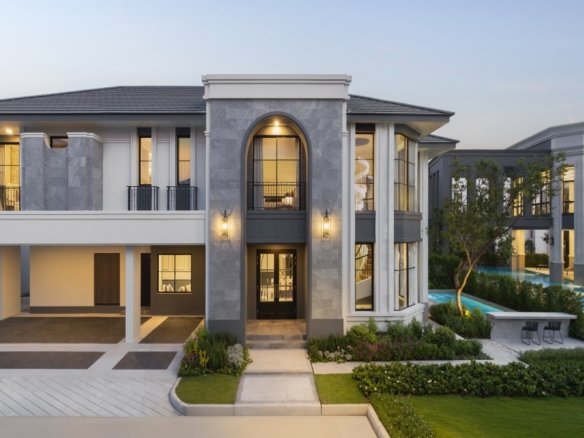 Modern luxury apartment complex with a grand arched entry, glass windows, and balconies, set among landscaped grounds and a pool area in the background.