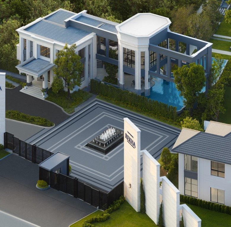 Aerial view of a gated luxury villa community with a central square and fountain modern white buildings and lush landscaping surrounding the entrance sign reading REKHA