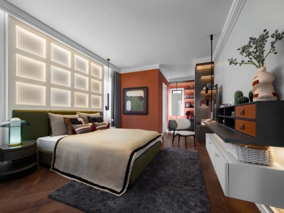 Contemporary hotel-style bedroom with a green upholstered bed, beige bedding, and an orange accent wall on the far side.