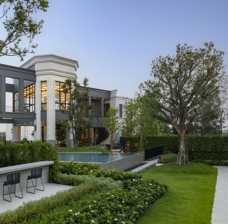 Modern two story home with large windows and a rectangular pool set in a manicured garden