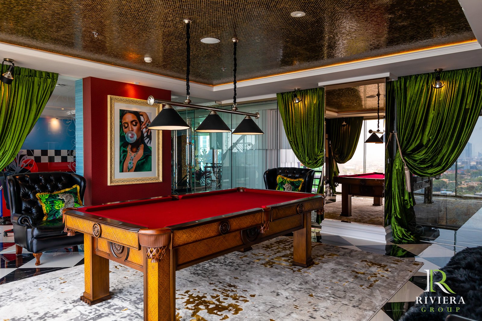 Riviera-Ocean-Drive-Pattaya 26 Luxurious game room with red felt pool table, black tufted chairs, and green velvet curtains with a city view outside